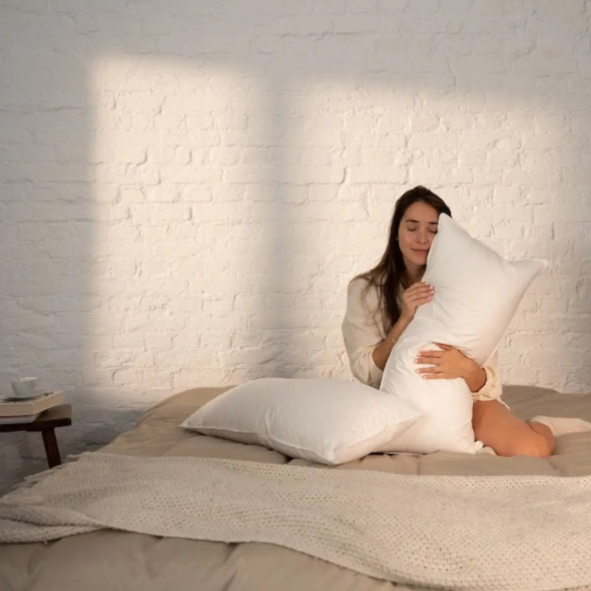 Das Cosy Mikrofaser Kissen in der Hand einer Frau auf einem Bett.